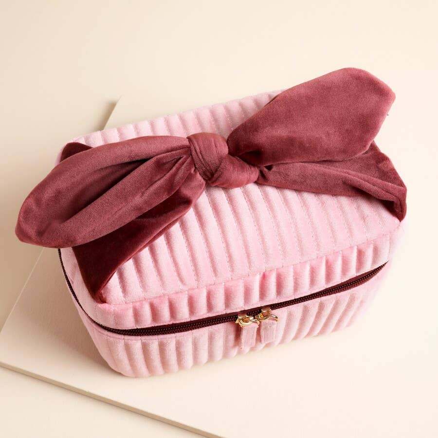 Top view of pink and red velvet bow washbag with twin zip closure.