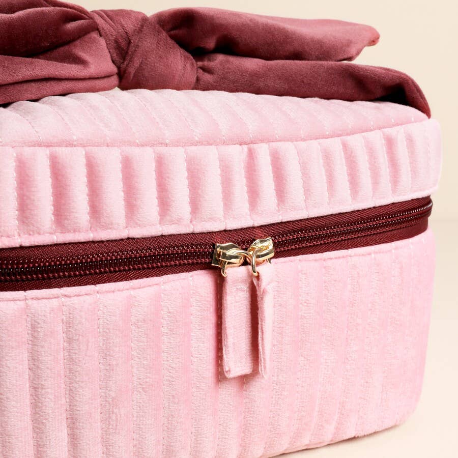 Close-up of gold zip detailing on pink and red velvet makeup bag.