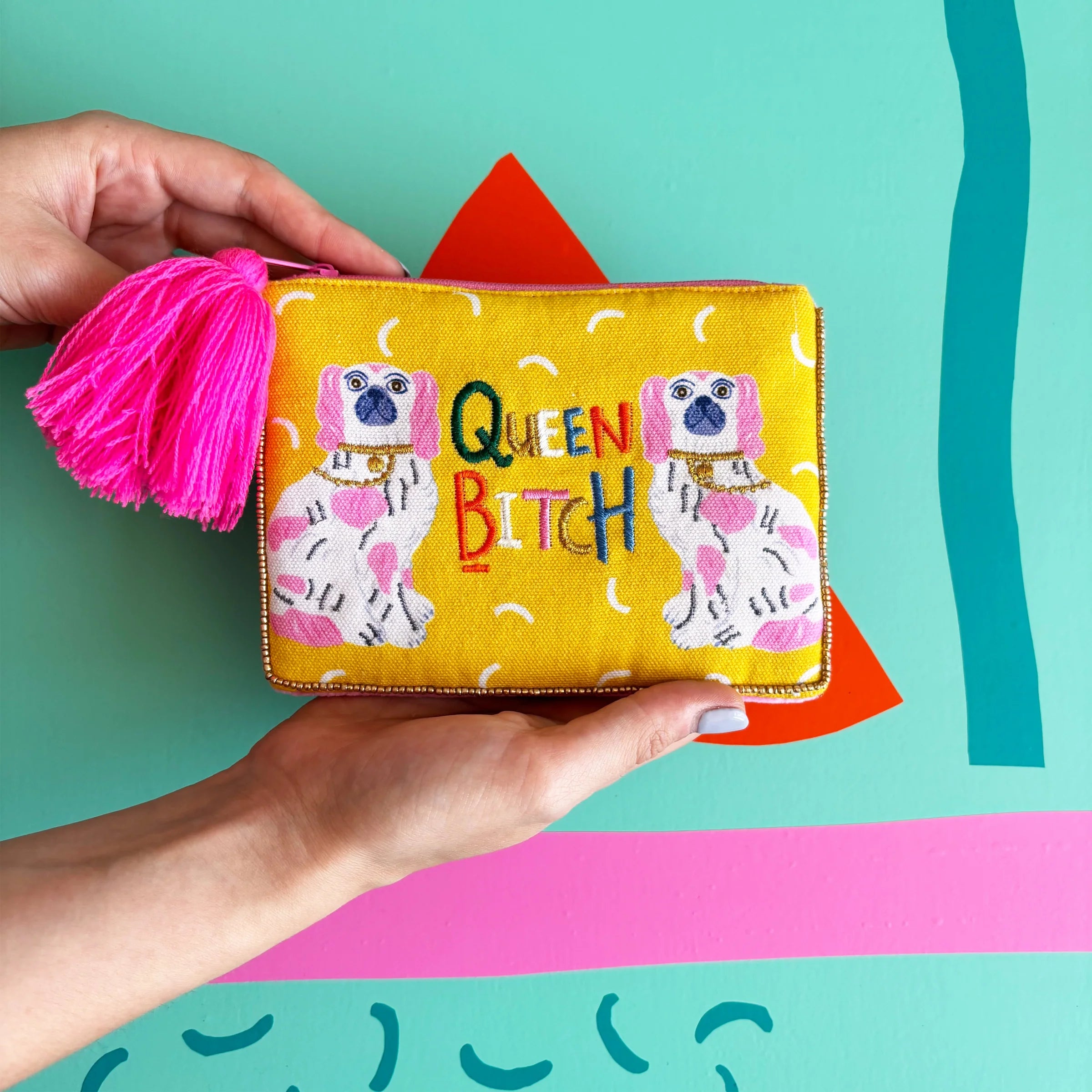 Queen Bitch Pouch with yellow cotton front and pink tassel held in hands.