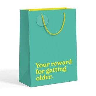 Teal medium gift bag with gold slogan text on white background.