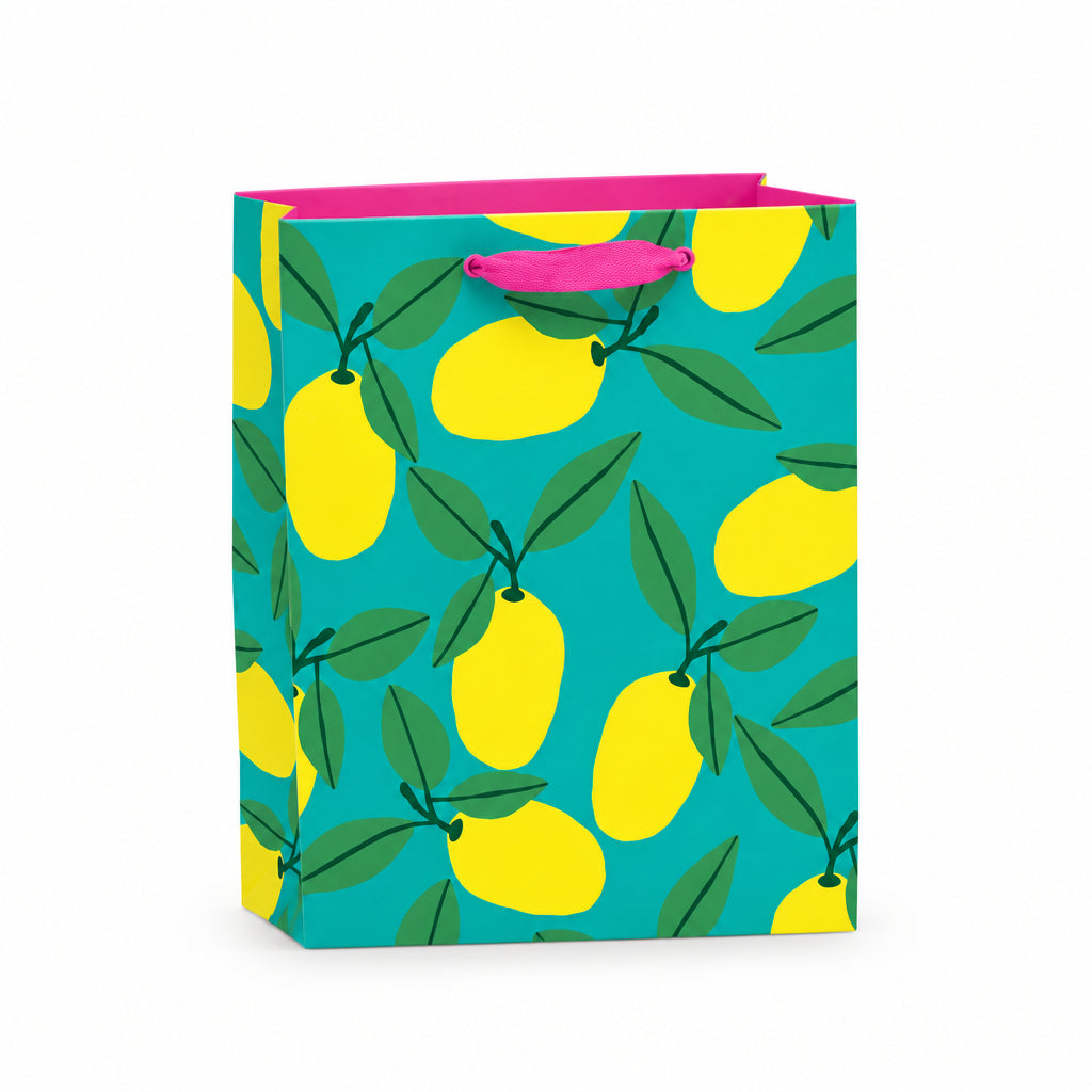 Small recyclable lemon gift bag with Anne Bentley’s bold yellow fruit and green leaf illustrations on a turquoise background, featuring pink grosgrain ribbon handles and a matching gift tag.