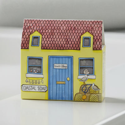 Seaside house-shaped soap in coastal cottage packaging on grey surface