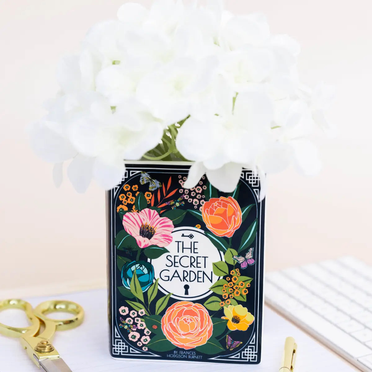 Front view of Secret Garden ceramic book vase with white flowers, featuring vibrant floral design inspired by the novel.