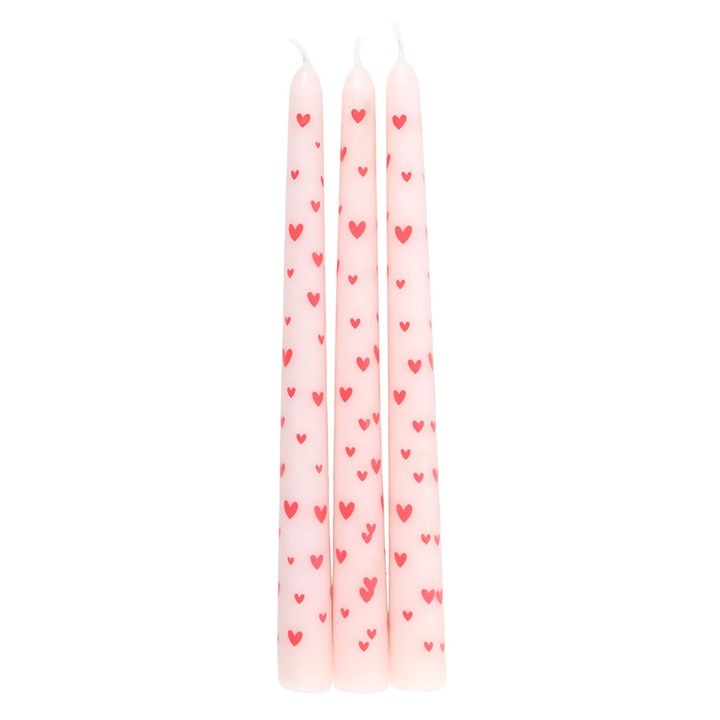 Three pink taper candles decorated with red hearts, standing upright on white background, ideal for romantic table settings or home décor.

