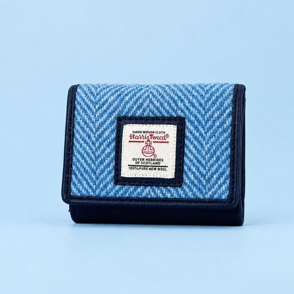 Angled view of sky blue Harris Tweed trifold purse showing herringbone pattern and front flap.