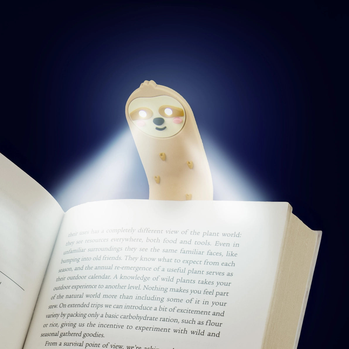 LED Sloth Reading Light glowing in the dark – illuminating book pages during nighttime reading.