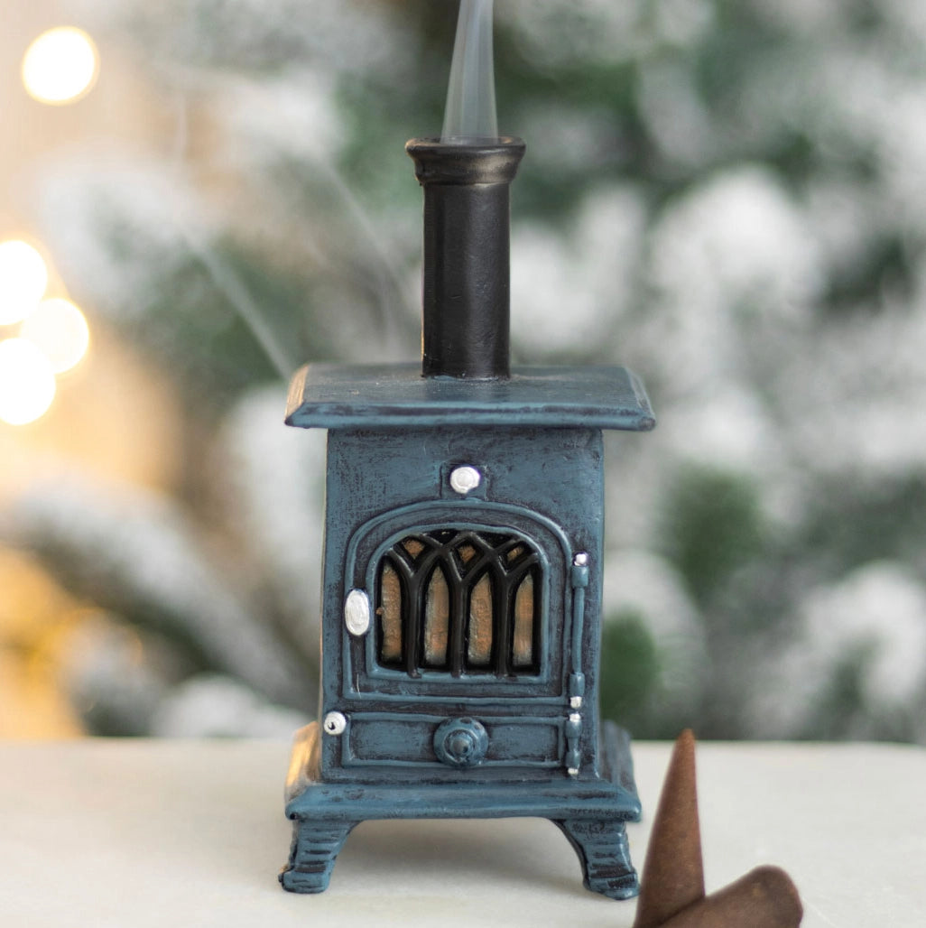 Styled burner with festive background and smoke – smoking stove incense burner in front of blurred Christmas tree lights.