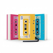 Three colourful cassette-style notebooks in pink, yellow, and blue, standing upright and designed to look like retro mixtapes.