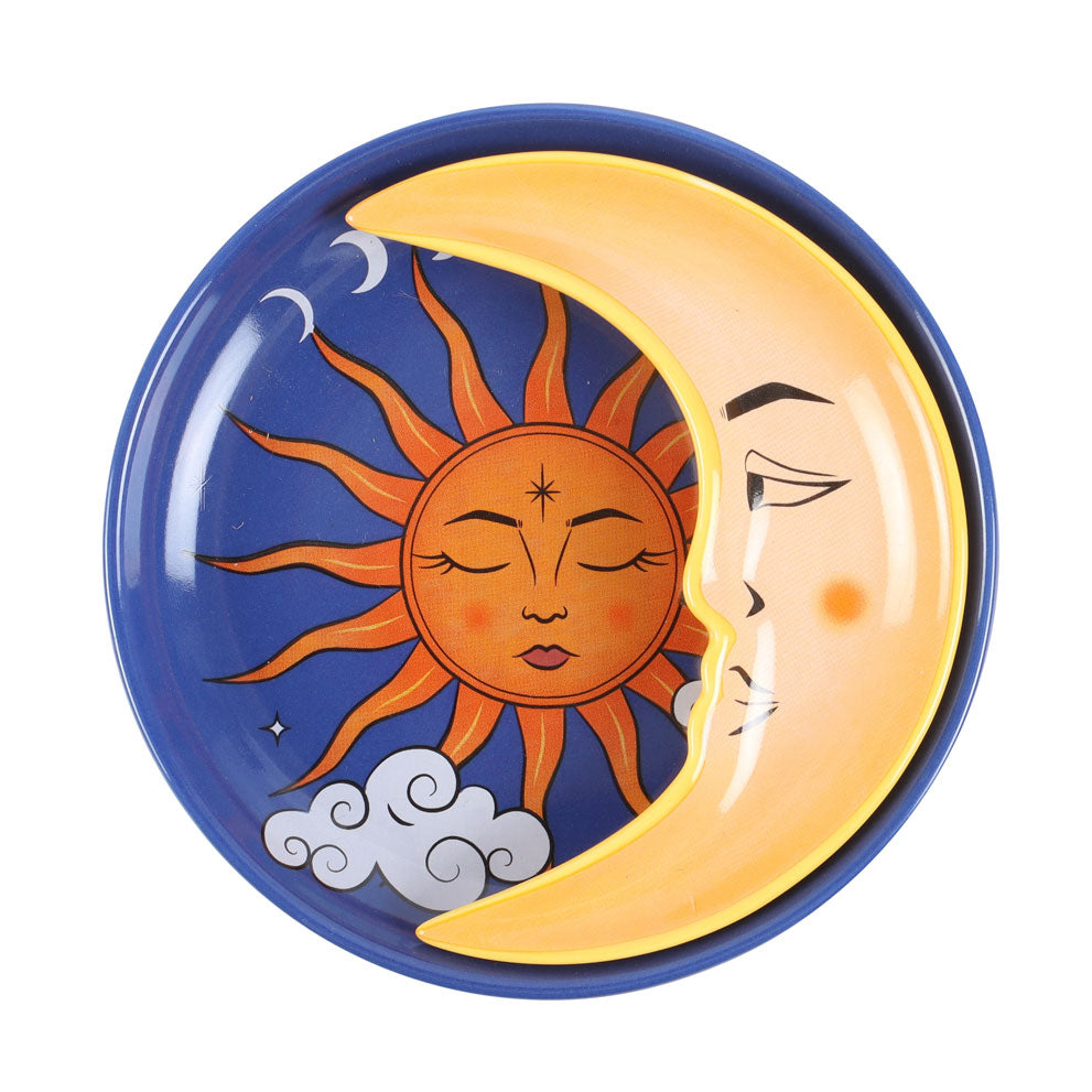 Top-down image of celestial stacking trinket dish with crescent moon overlaying sun illustration on blue circular base with cloud and moon phase details.