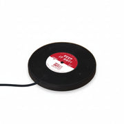 Close-up side view of the Vinyl Mug Warmer shaped like a black vinyl record with red and white centre label reading “Keep It Hot”, shown plugged in on a wooden surface.