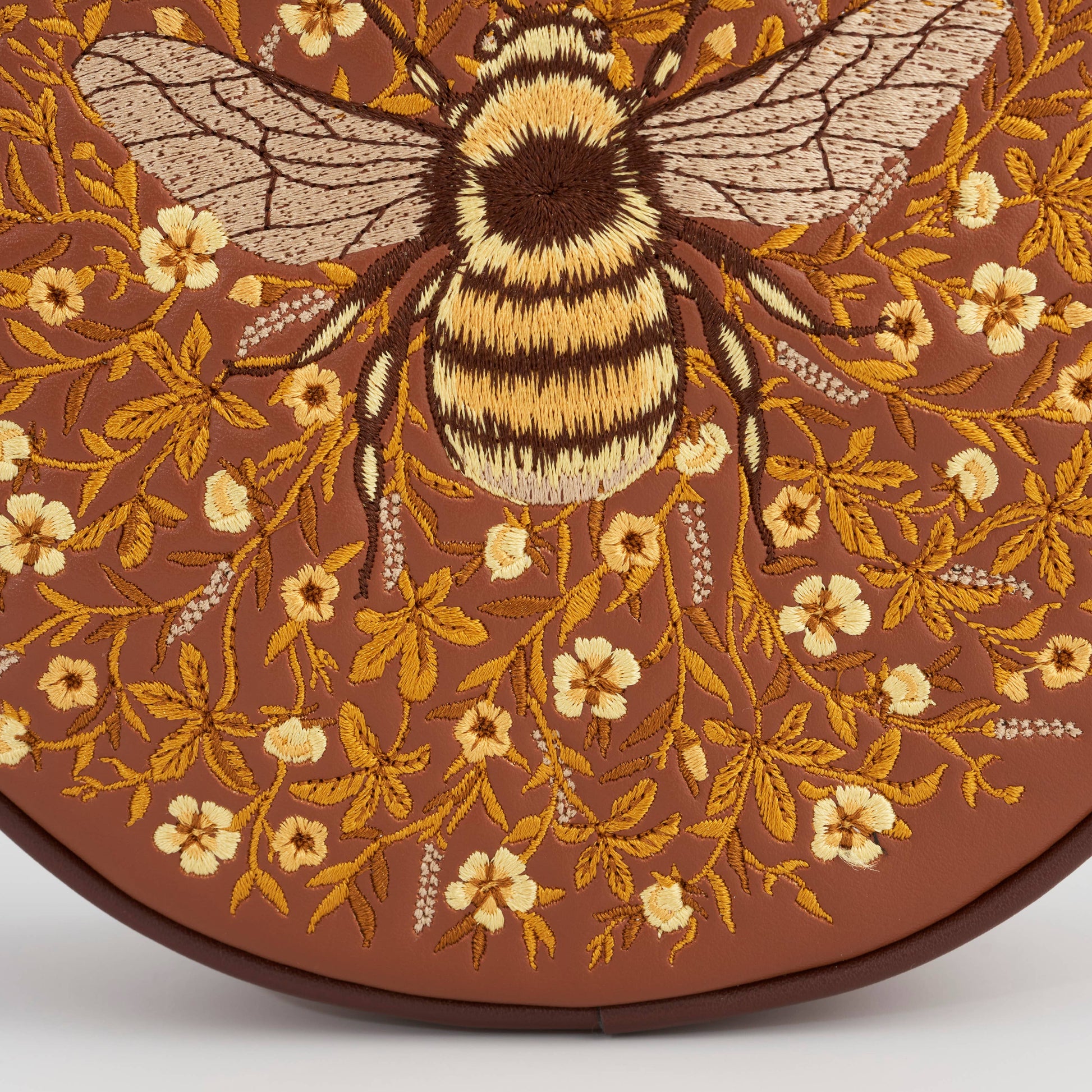 Detail of the gold embroidered bumble bee among honey coloured flowers