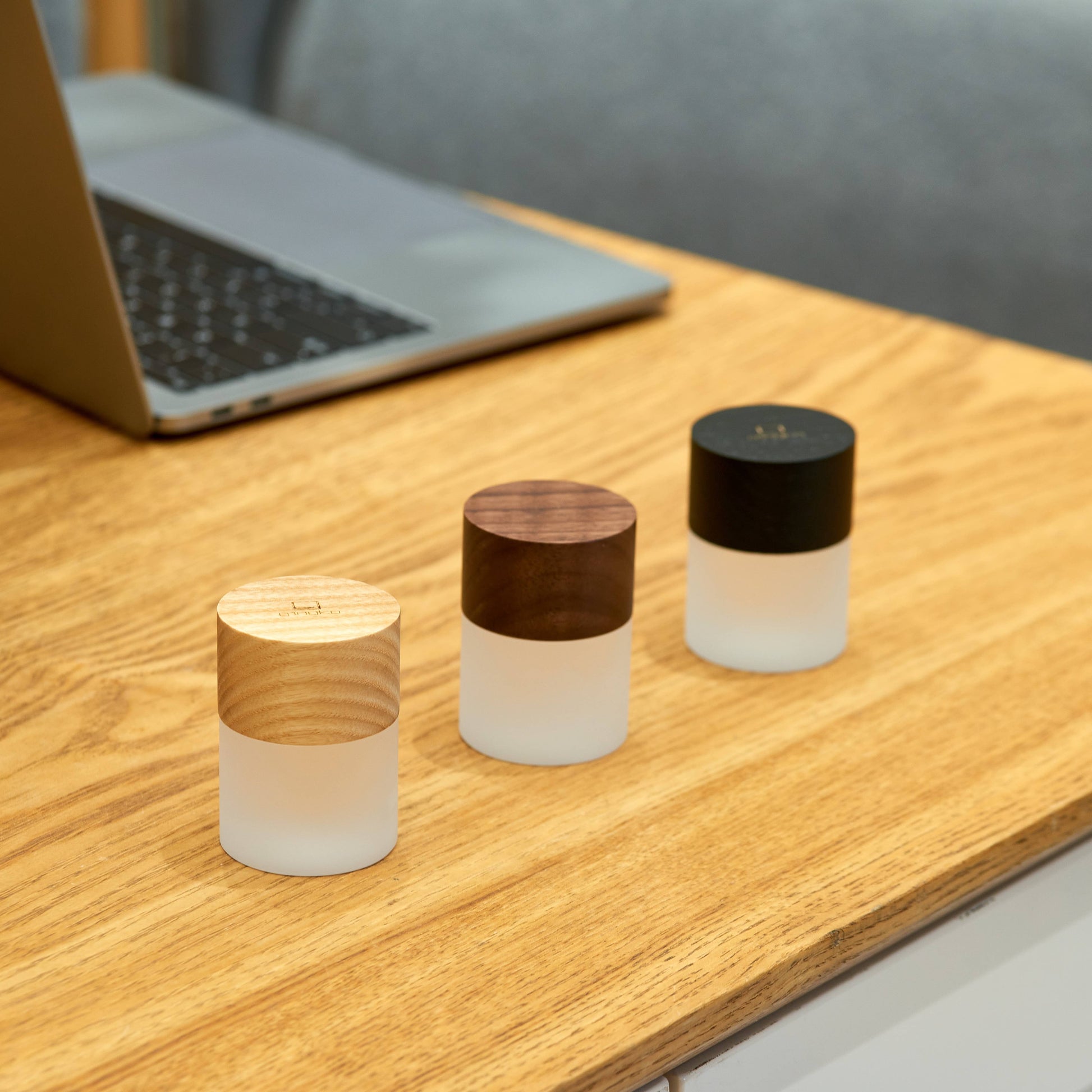 Three sizes of Lemelia light unlit on a desk beside a laptop