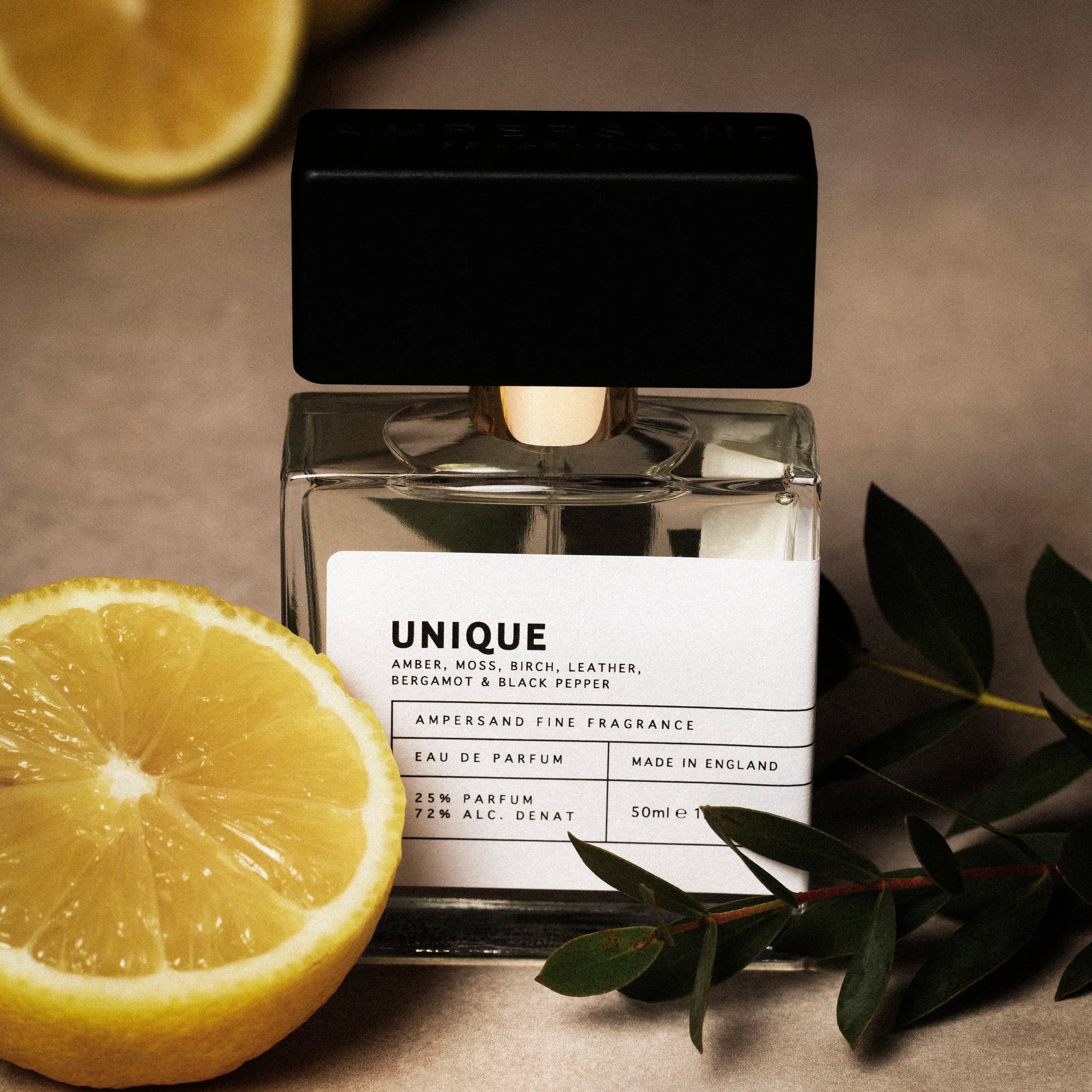 Unique perfume with lemons and green leaves on dark background