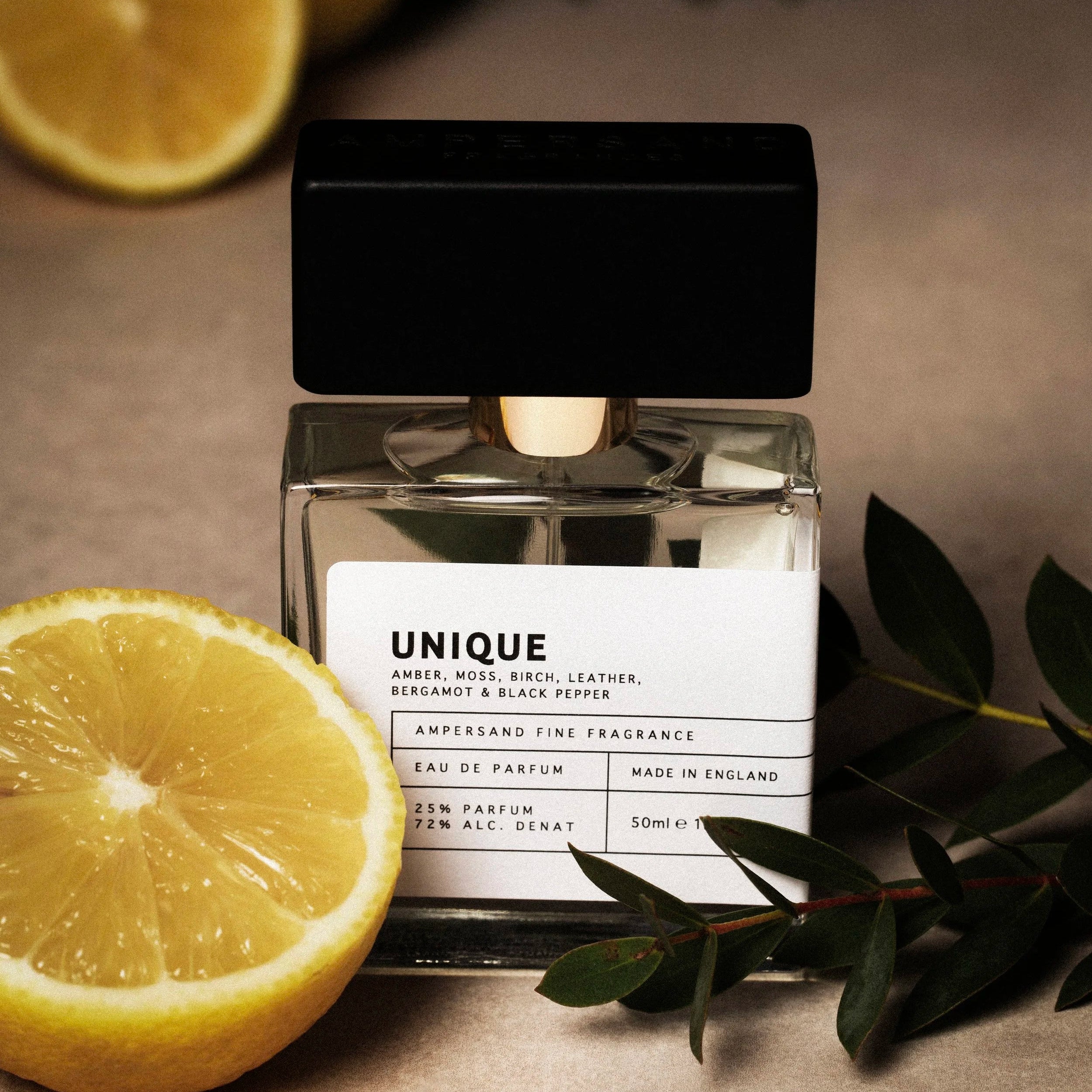 Unique perfume with lemons and leaves on dark background