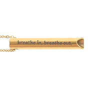 Close-up of gold breathing necklace pendant engraved breathe in, breathe out, on white.