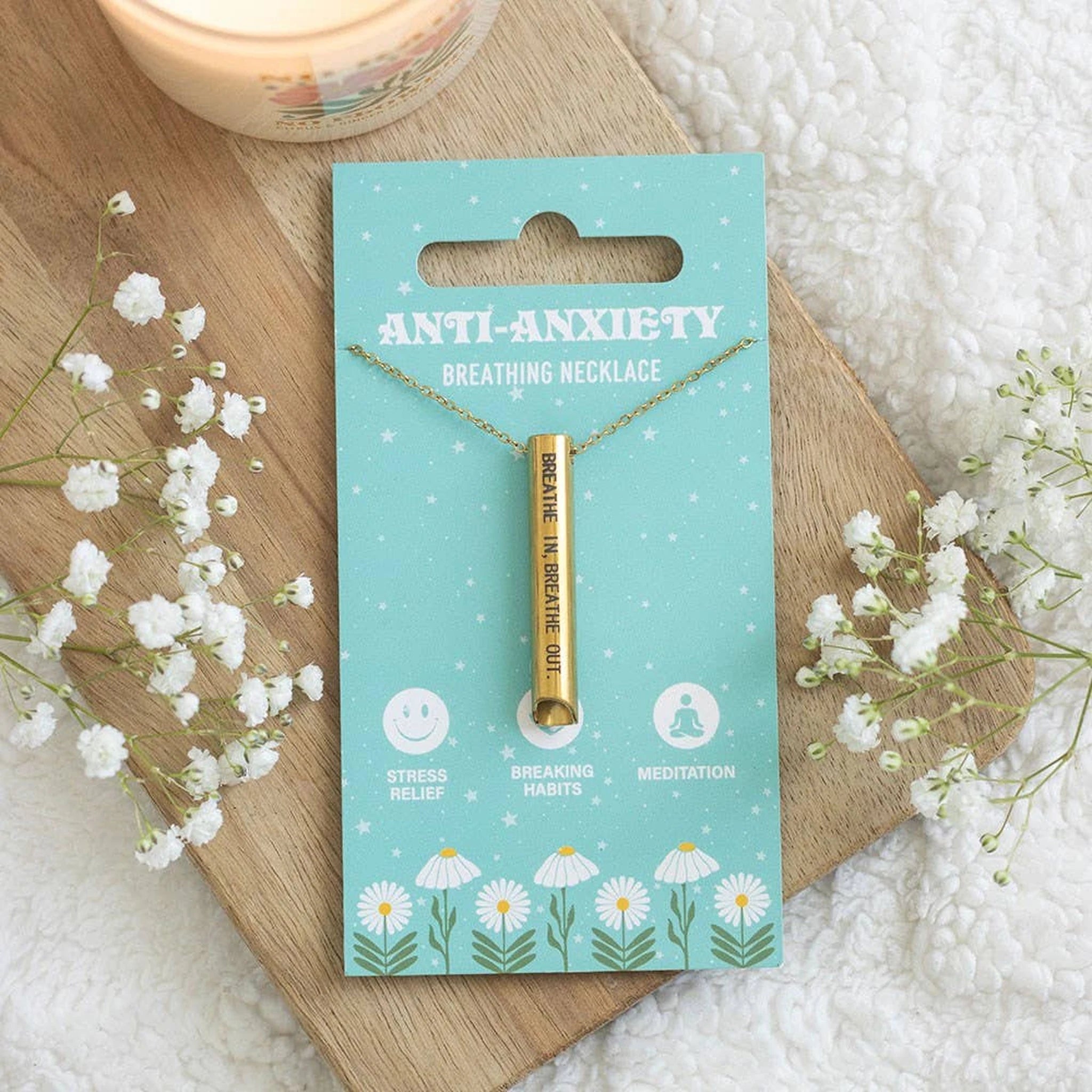 Anti-anxiety breathing necklace styled on a wooden board with white gypsophila and soft cream blanket.