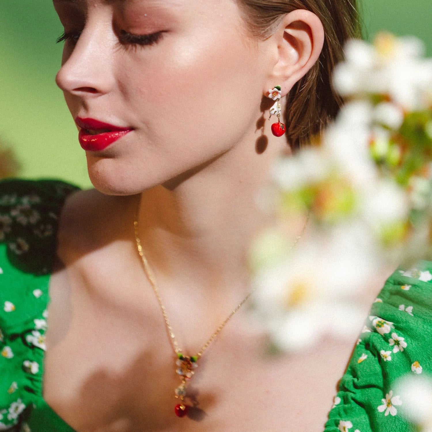 Model wearing Apple Blossom & Mouse Drop Earrings and matching necklace in green floral dress.