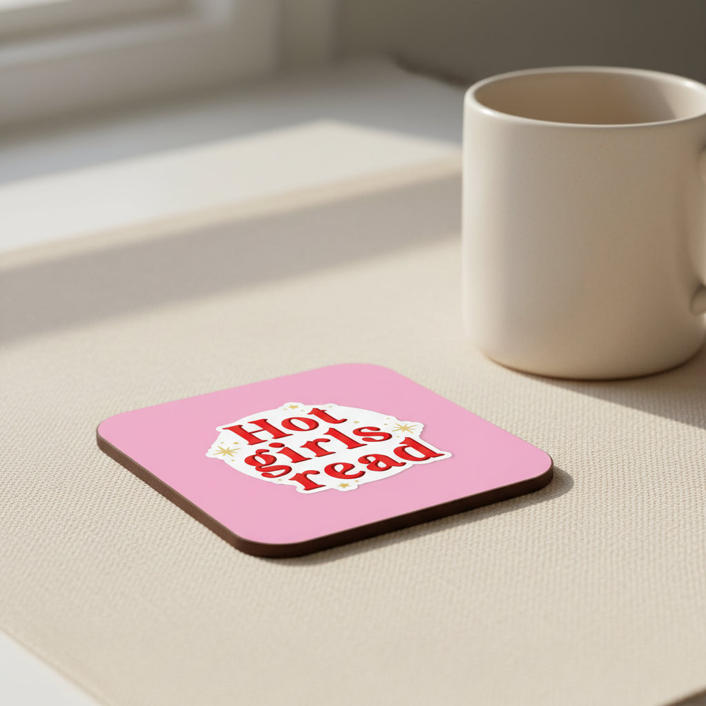 A square pink coaster or tile with rounded corners, featuring a white die-cut sticker design in the center that reads 'Hot girls read' in red lettering with small gold star accents.