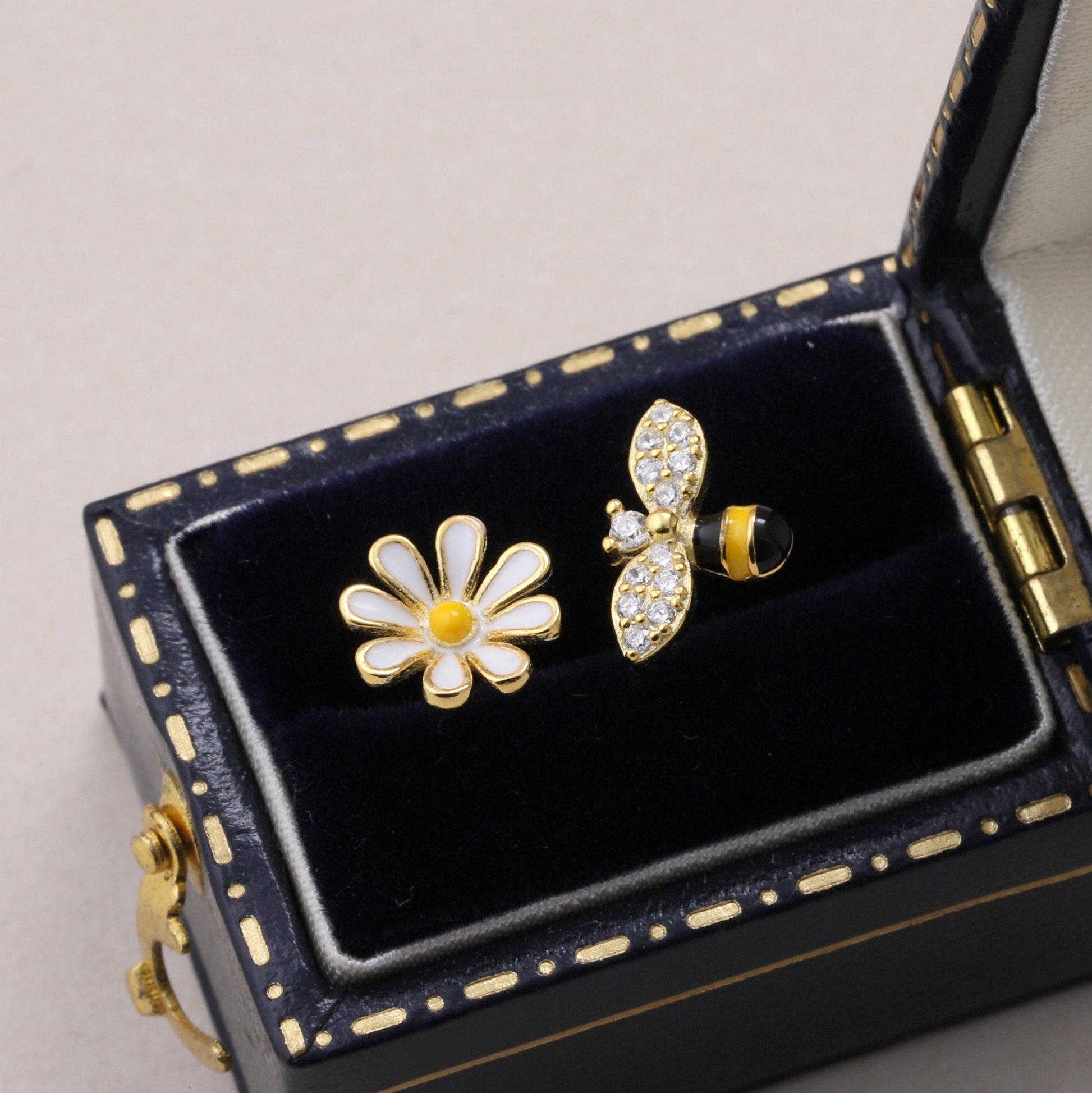 Gold enamel bee and daisy earrings in dark jewellery box with gold trim