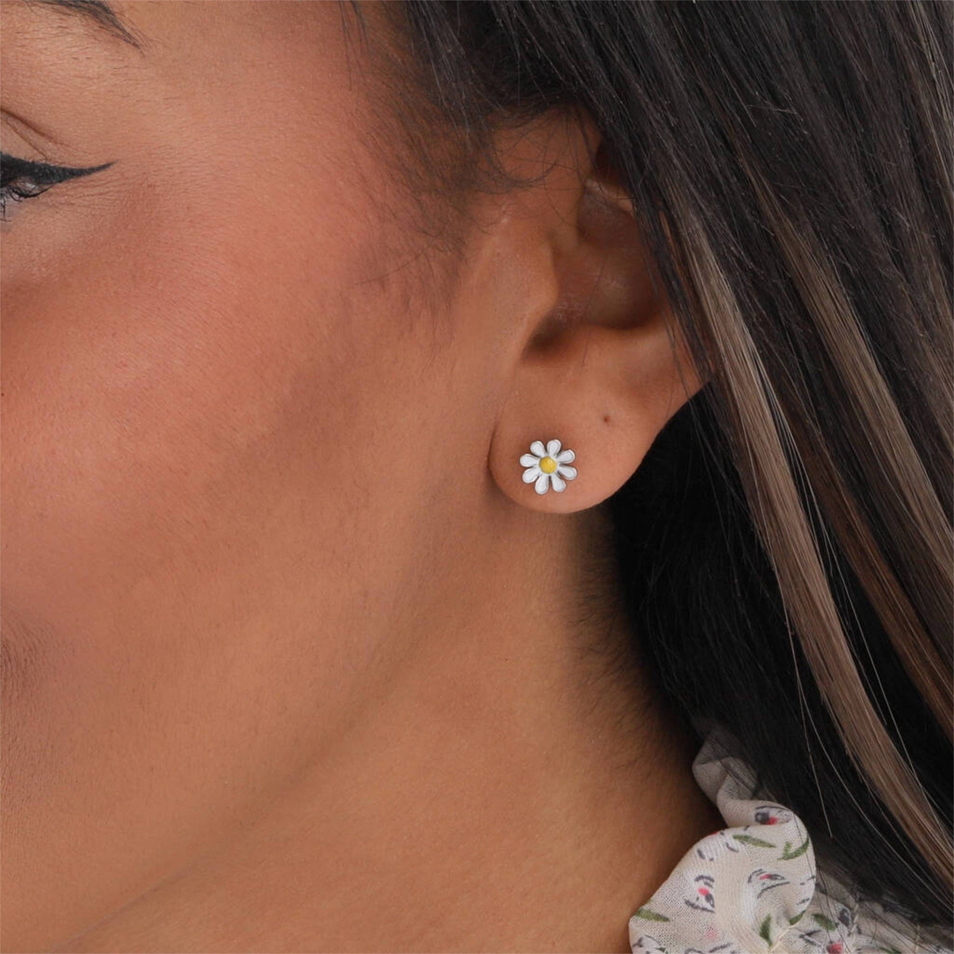 Woman wearing silver enamel daisy stud earring in lifestyle close-up