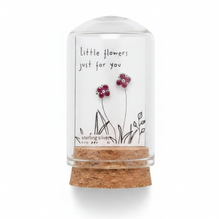 Small glass container with dried flowers and a label on a textured surface