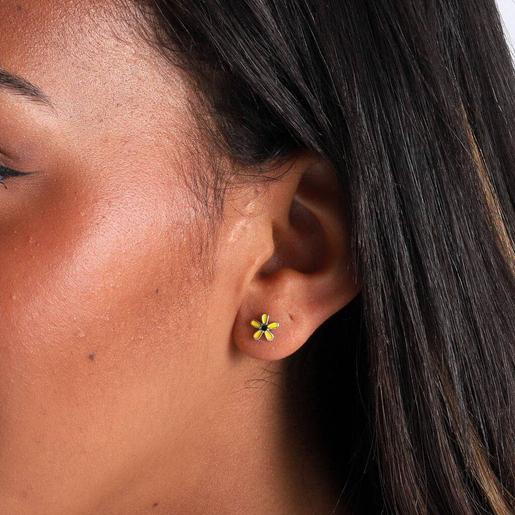 Woman wearing yellow daisy stud earring in lifestyle close-up