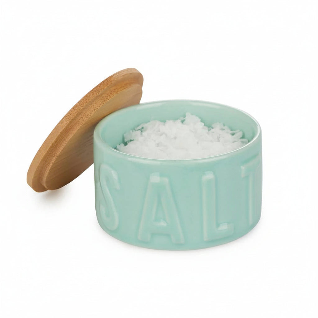 Mint green salt container with wooden lid on a white background