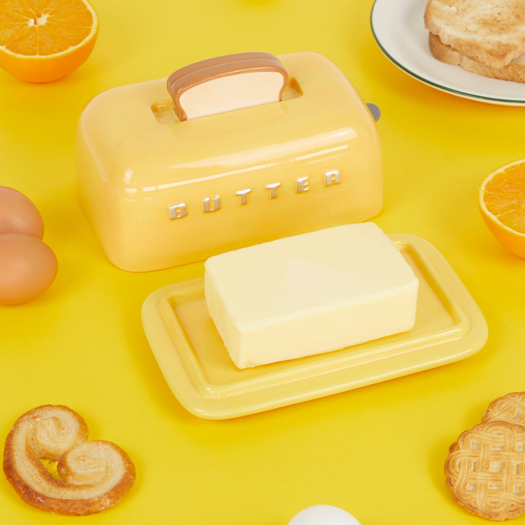 Toaster butter dish on a yellow flatlay with eggs, oranges, toast and pastries