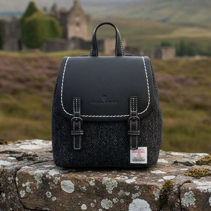 Black herringbone Harris Tweed Mini Jura backpack on stone wall in the Highlands