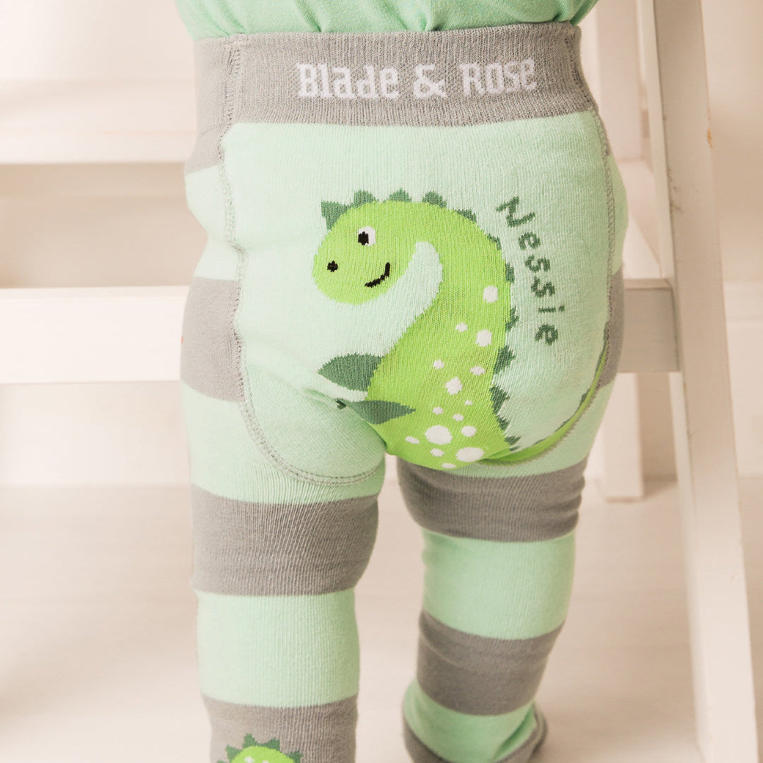 Close up of the green Nessie leggings and striped socks on a standing baby