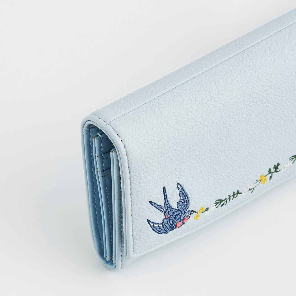 Side view showing the embroidered bird detail and folded edges.