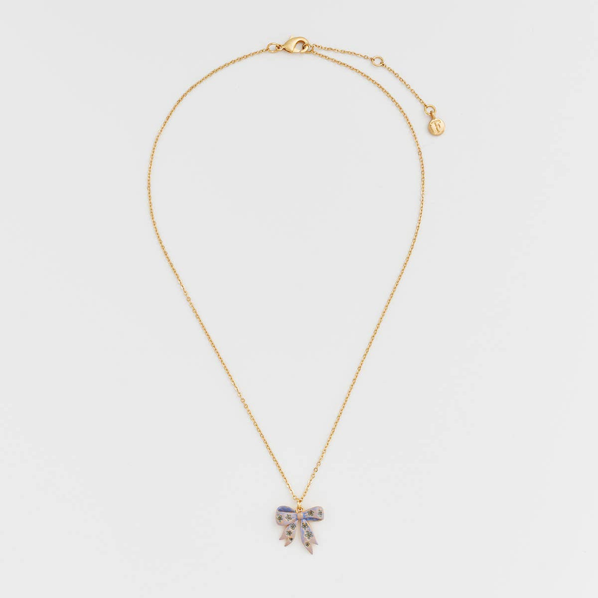 Full view of gold bow pendant necklace with extender