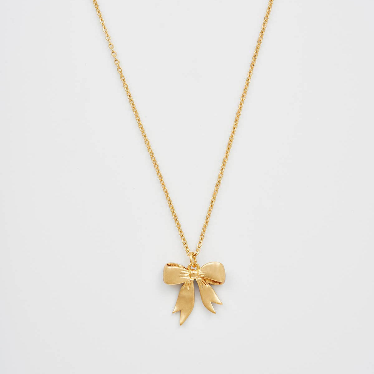 Reverse of the bow pendant showing the plain 22ct worn gold-plated back