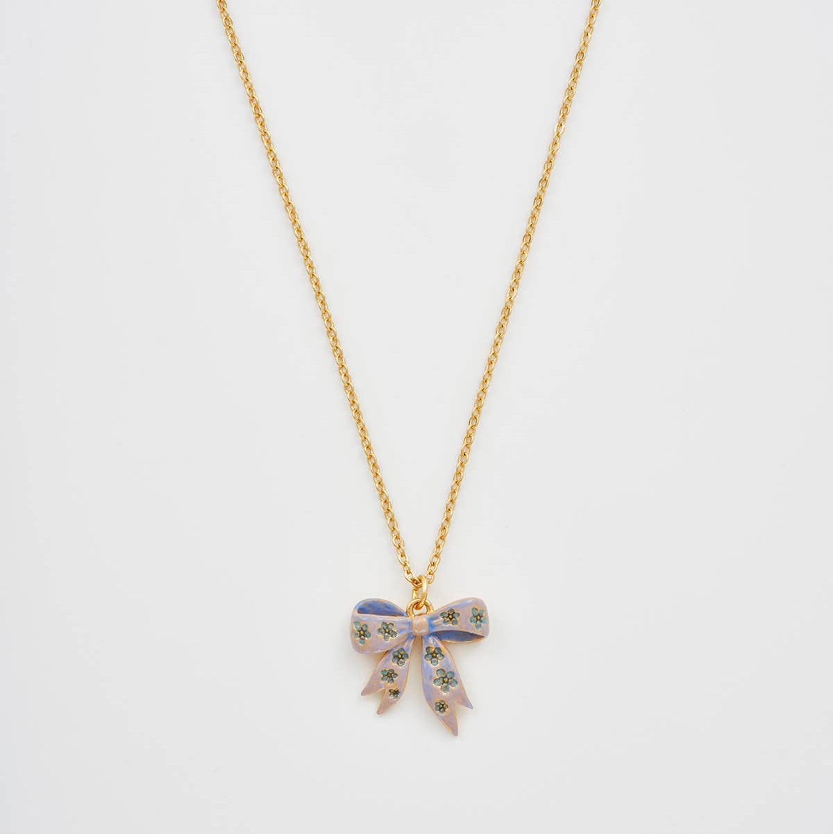 Gold bow pendant necklace on white background