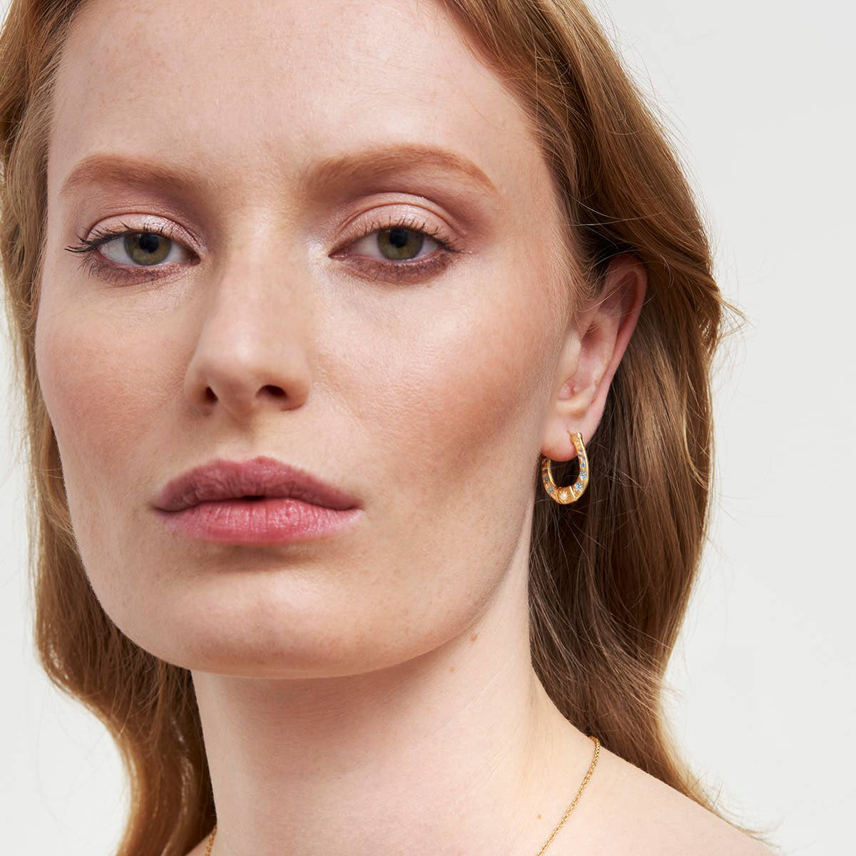 Horseshoe hoop earrings worn on a model