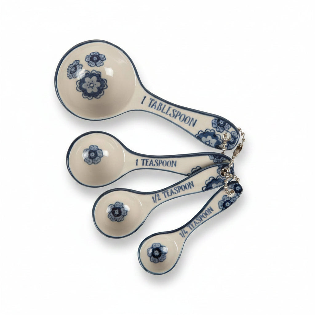 Set of four ceramic measuring spoons with blue floral designs on a white background