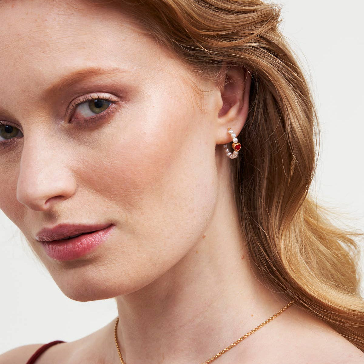 Heart pearl hoop earrings worn on a model