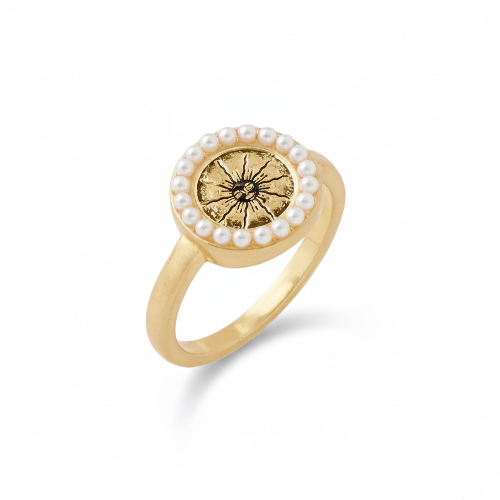 Celestial Ring side view showing gold band and pearl-bordered sun charm on grey background