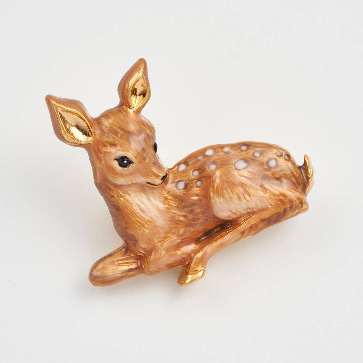 Close-up of fawn brooch showing golden enamel finish