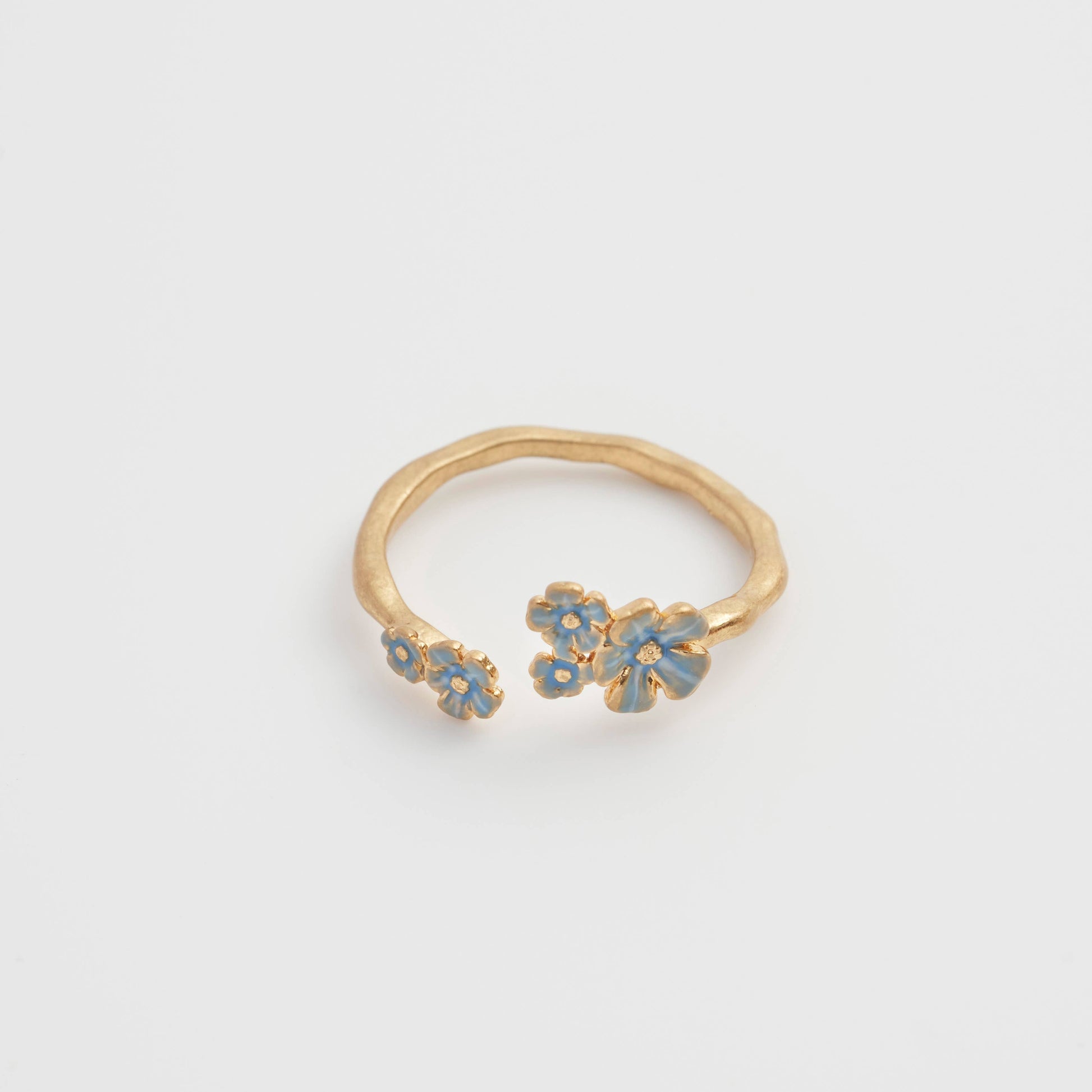Open gold Forget-Me-Not ring with blue enamel flowers in flat lay