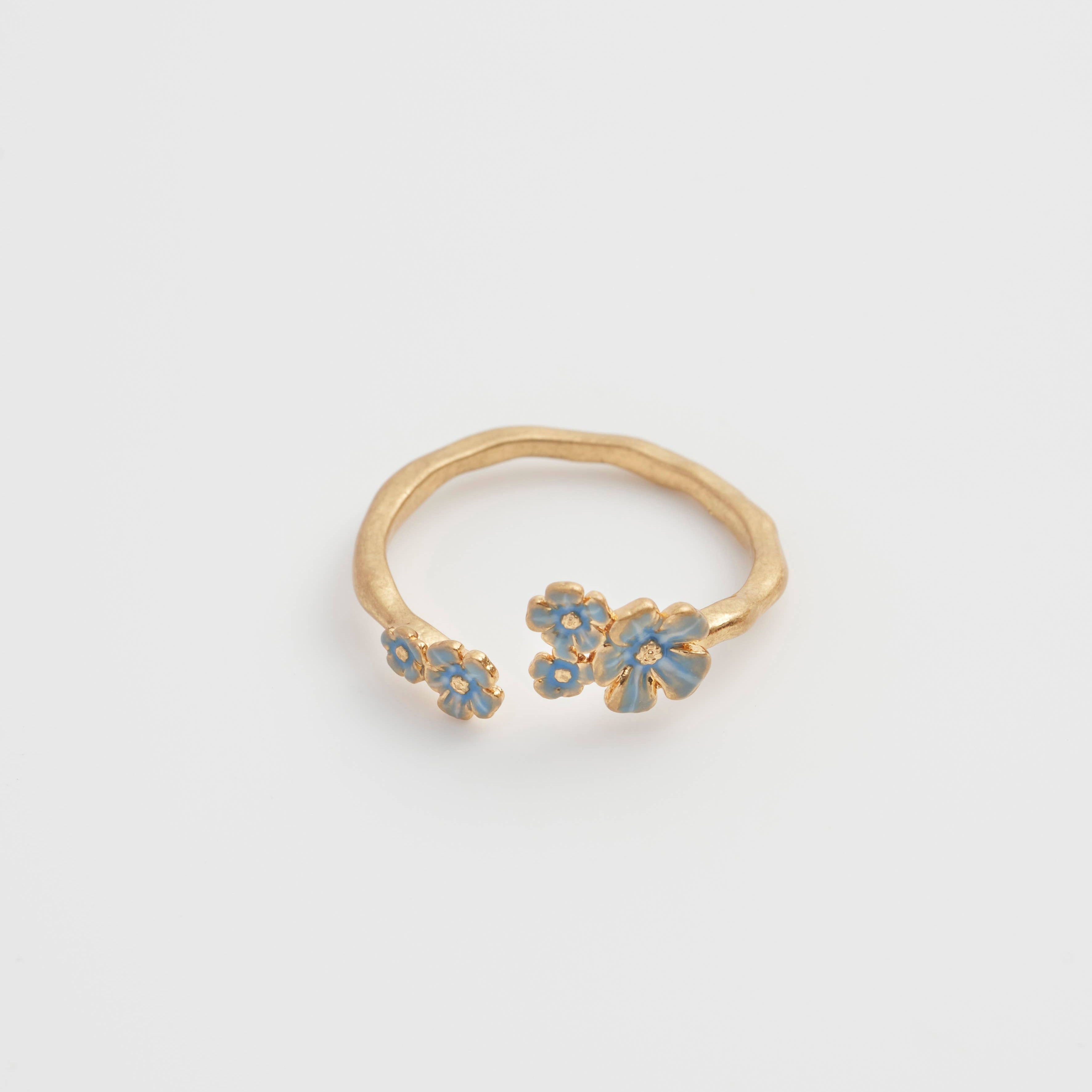Open gold Forget-Me-Not ring with blue enamel flowers in flat lay