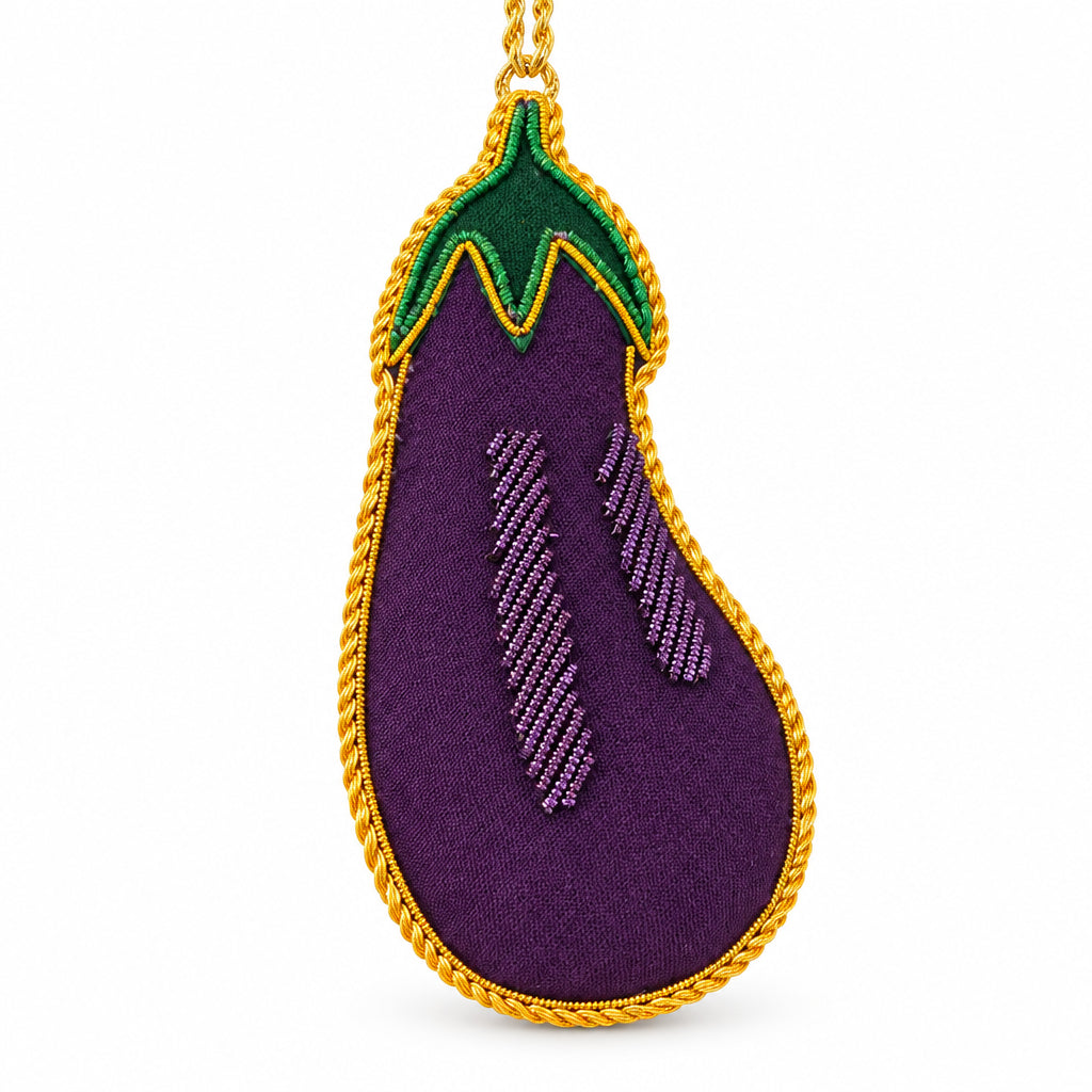 Aubergine embroidered decoration close up, showing the purple fabric and gold metal thread