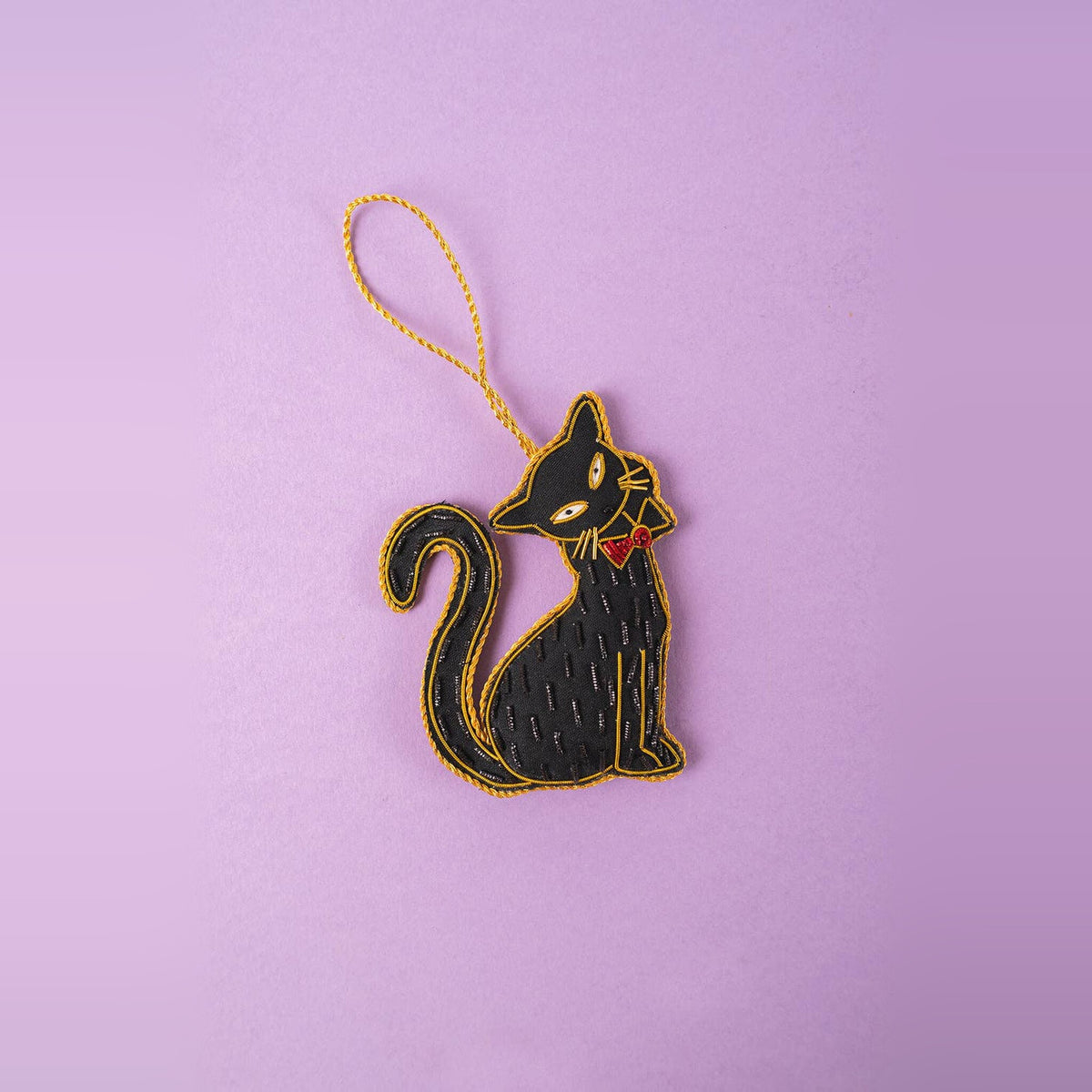 Fancy Black Cat embroidered Christmas decoration with red bow and gold outline on a lilac background