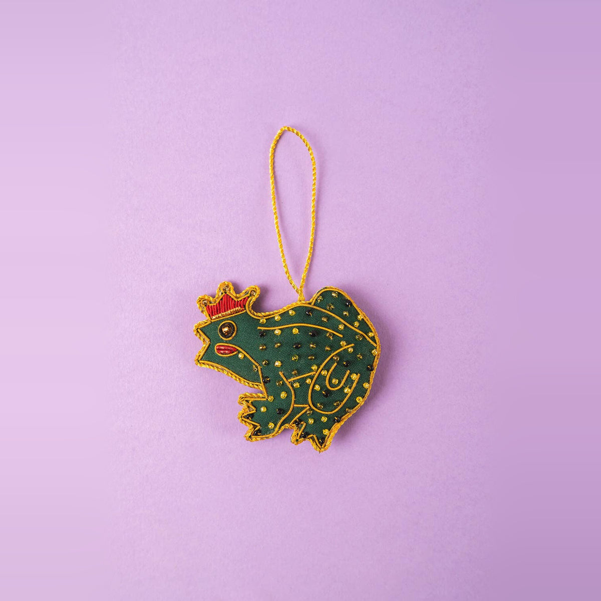 Frog Prince embroidered Christmas decoration, green with gold spots and red crown, on a lilac background