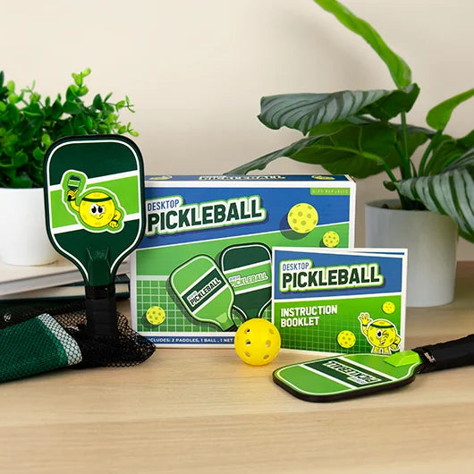Desktop Pickleball kit with paddles, ball and instructions on desk
