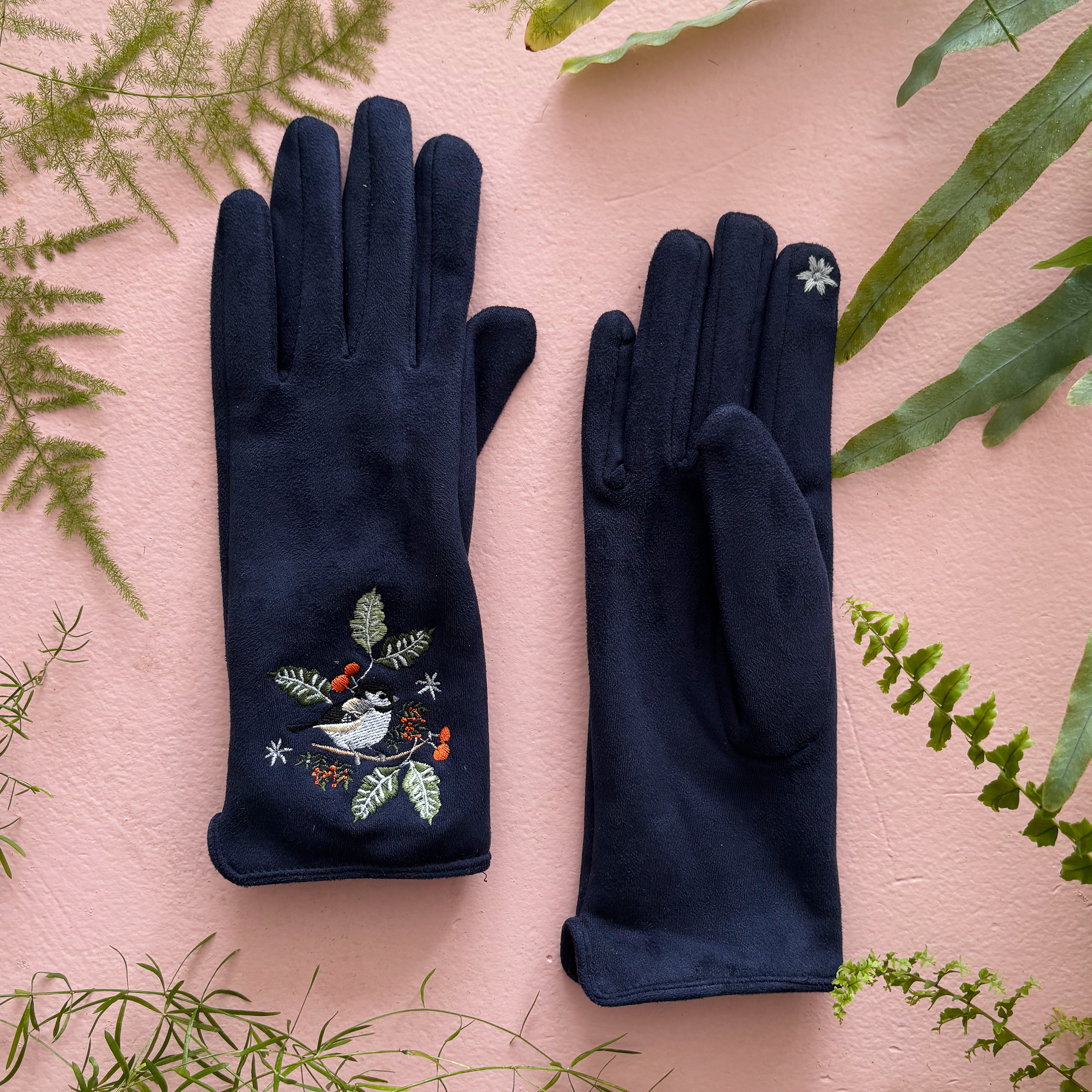 Both bird gloves flat showing embroidered fronts on pink background with greenery