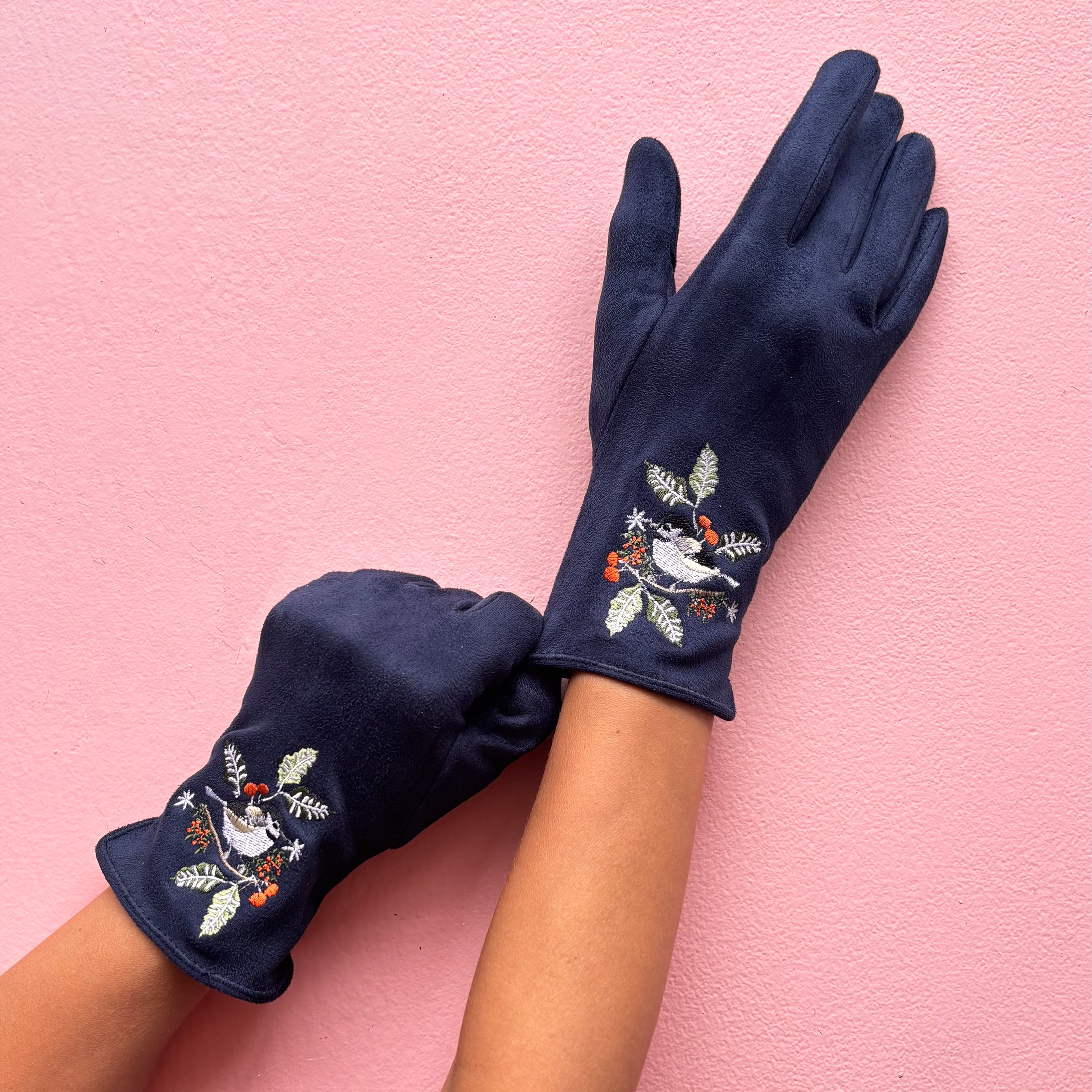 Navy embroidered bird gloves worn on hands showing design on pink background