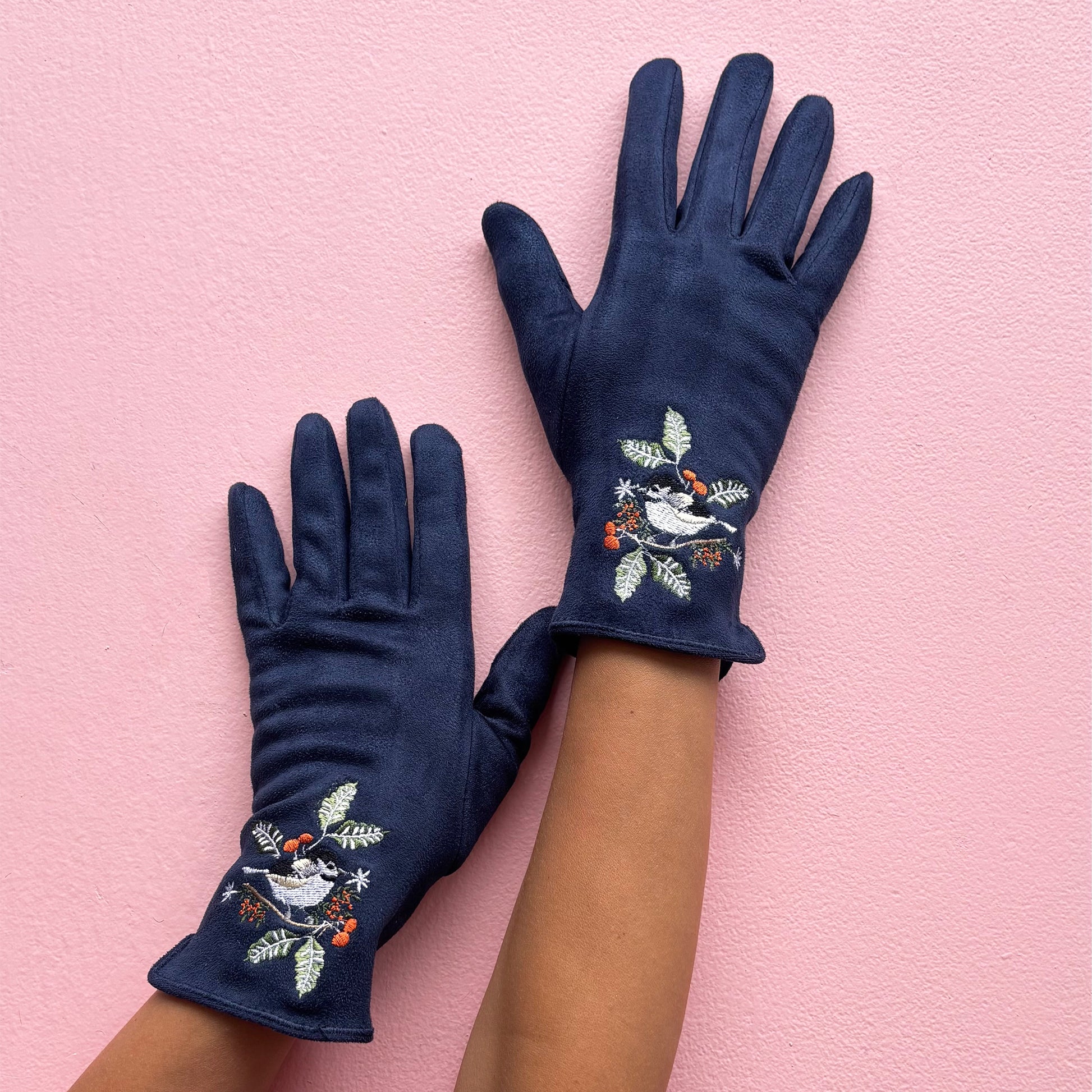 Bird gloves worn on hands with raised view against pink background