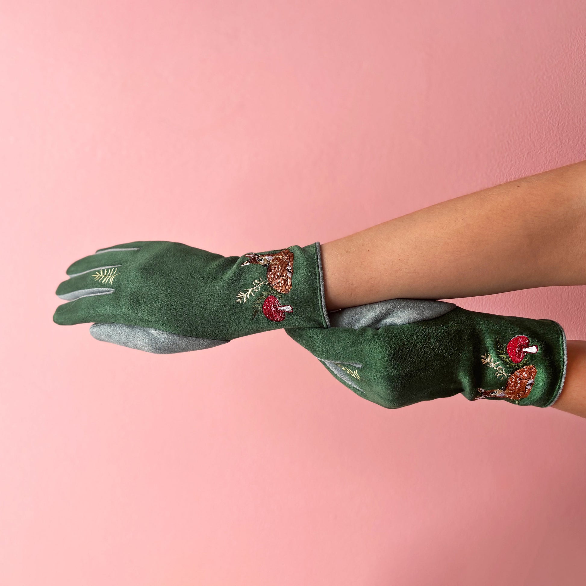 Deer gloves side profile on hands showing embroidery on pink background