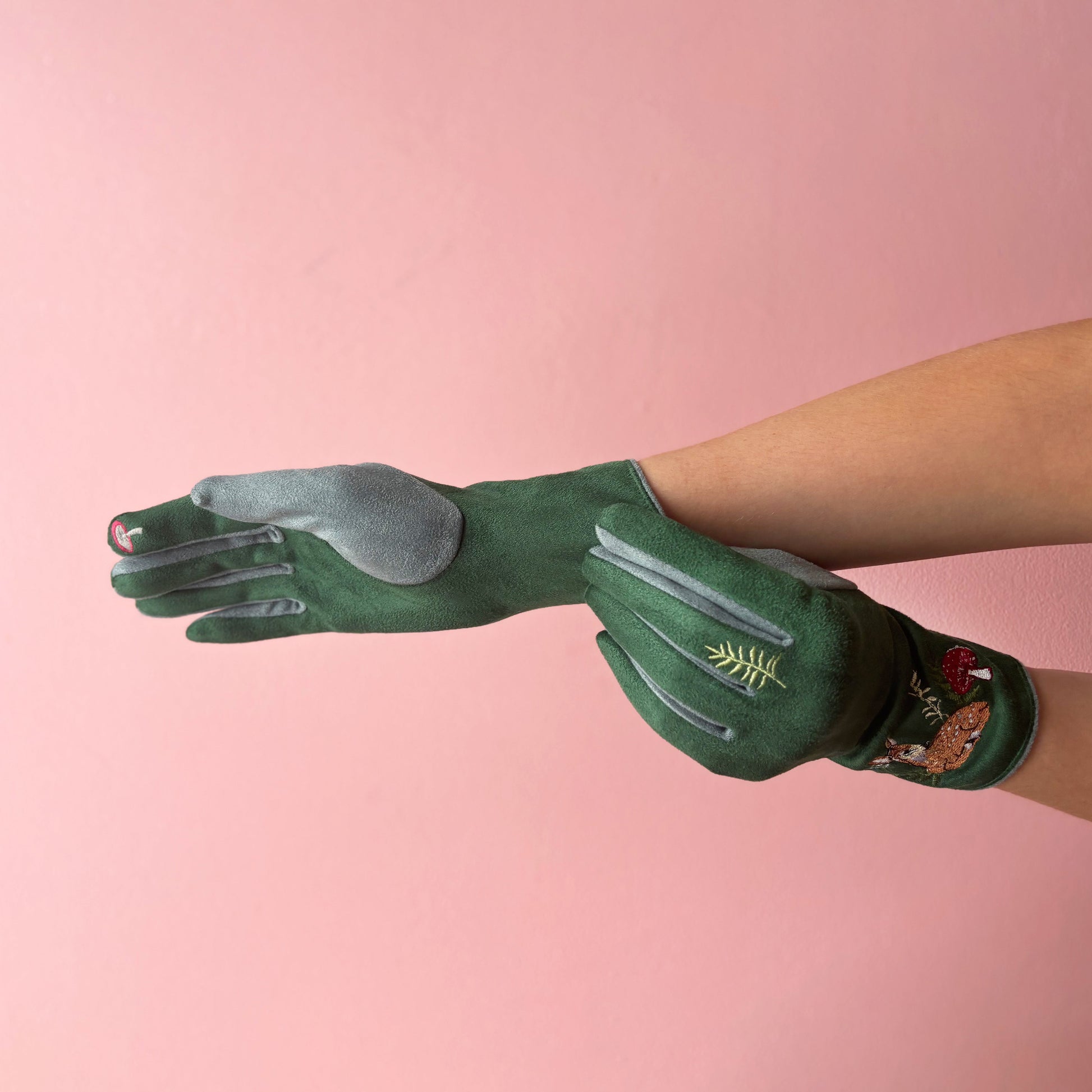 Deer gloves overlapping hands showing grey palm panel on pink background